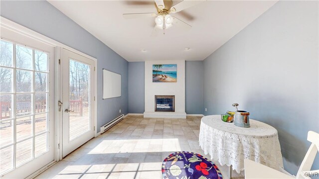 interior space with a baseboard radiator, baseboards, a ceiling fan, and a glass covered fireplace