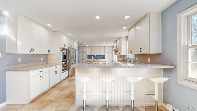 kitchen with a peninsula, white cabinets, light countertops, and a kitchen breakfast bar