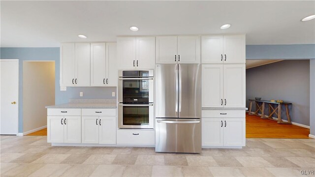 kitchen featuring recessed lighting, stainless steel appliances, white cabinetry, baseboards, and light countertops