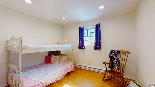 bedroom with a baseboard heating unit, wood finished floors, and recessed lighting