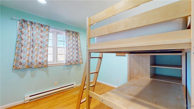 bedroom with baseboards, baseboard heating, and wood finished floors