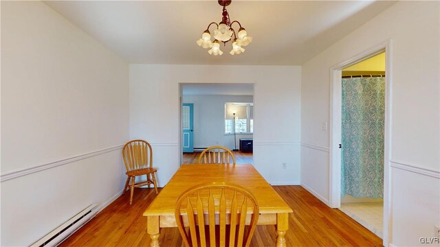 dining space featuring light wood-type flooring, a baseboard radiator, a chandelier, and baseboards