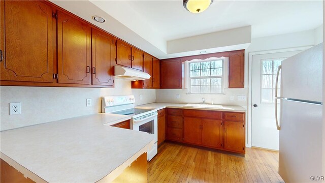 kitchen with white appliances, light countertops, under cabinet range hood, and a peninsula