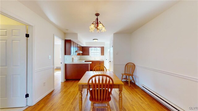 dining room featuring a baseboard heating unit, light wood-type flooring, and a chandelier