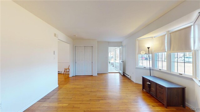 unfurnished room featuring light wood-type flooring, baseboards, and baseboard heating