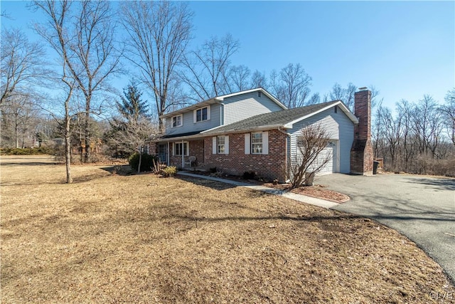 view of front facade featuring an attached garage, brick siding, driveway, a front lawn, and a chimney