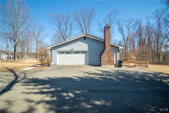 view of home's exterior featuring a deck, aphalt driveway, and a chimney