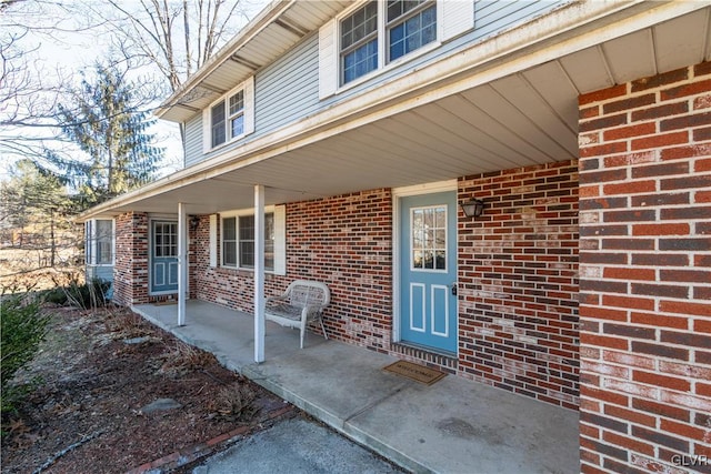 entrance to property with brick siding and a porch