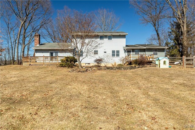 rear view of house featuring fence, a deck, and a yard