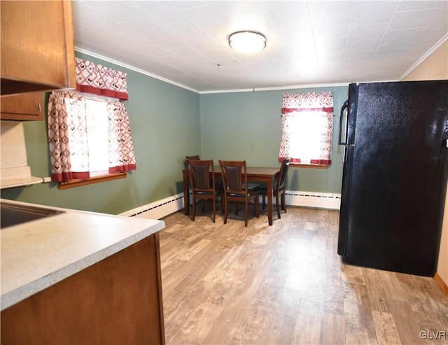 dining room featuring light wood-style flooring, a baseboard heating unit, and crown molding