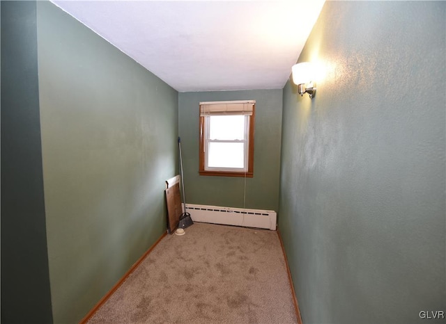 empty room featuring a baseboard heating unit, carpet floors, and baseboards