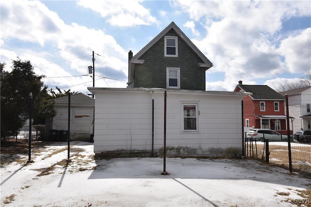 snow covered property featuring fence and a detached garage