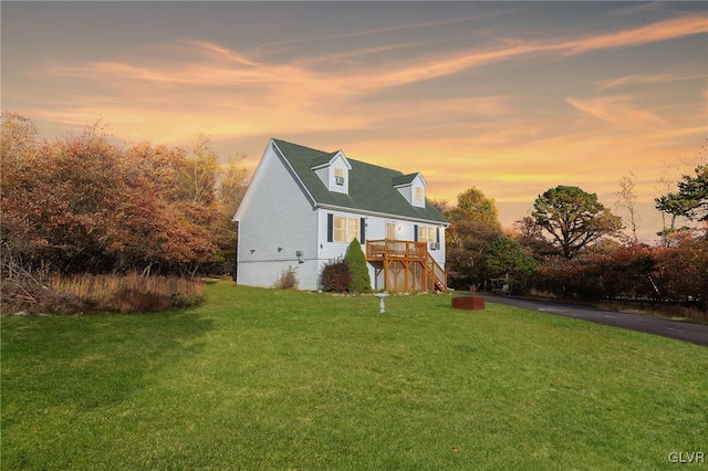 cape cod home with a lawn and stairway