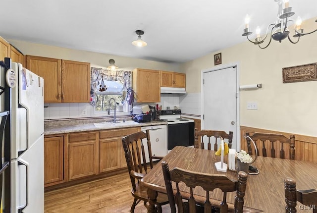 kitchen featuring a notable chandelier, light wood-style flooring, a sink, white appliances, and under cabinet range hood