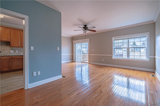 unfurnished living room with light wood-style floors, crown molding, and baseboards