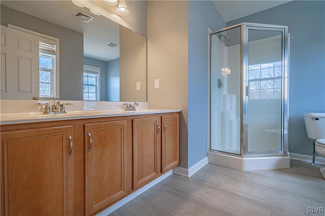 full bathroom with visible vents, toilet, a stall shower, a sink, and wood finished floors