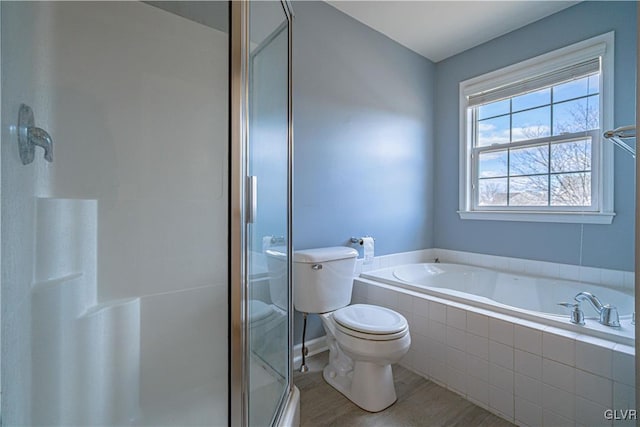 full bath featuring a garden tub, a shower stall, toilet, and wood finished floors