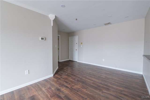 spare room with dark wood-style flooring, visible vents, and baseboards