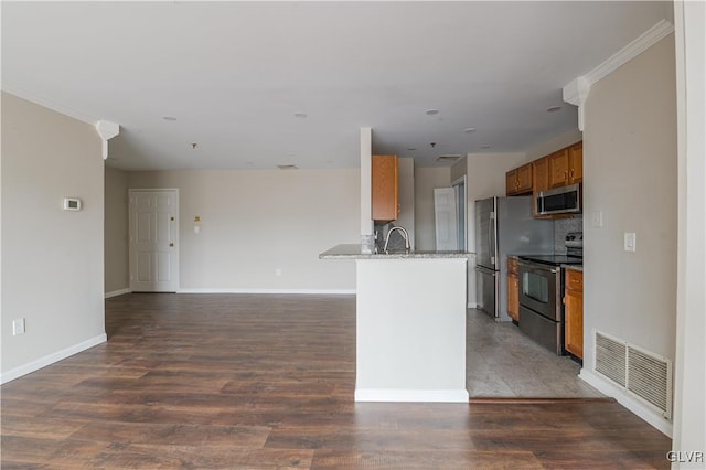 kitchen with brown cabinets, stainless steel appliances, visible vents, a sink, and wood finished floors