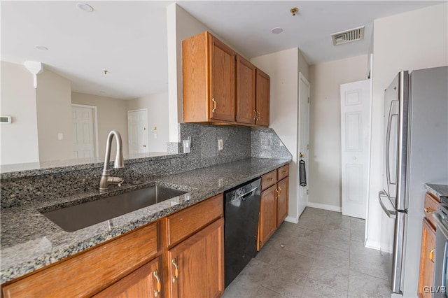 kitchen with visible vents, brown cabinetry, dishwasher, freestanding refrigerator, and a sink