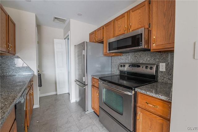 kitchen featuring brown cabinets, visible vents, stainless steel appliances, and decorative backsplash