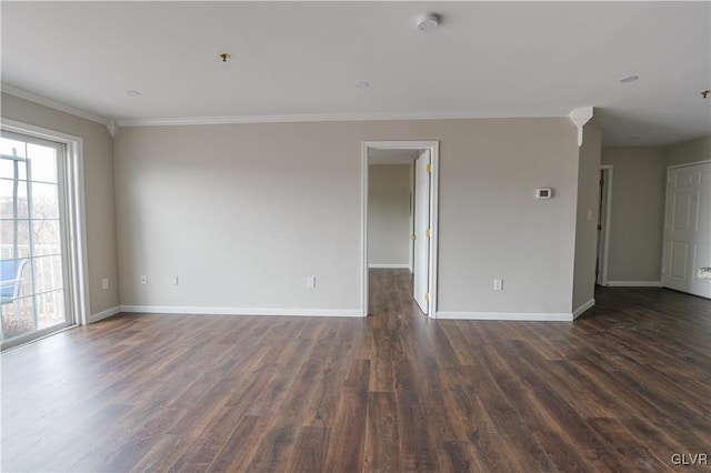 spare room with ornamental molding, dark wood-style flooring, and baseboards