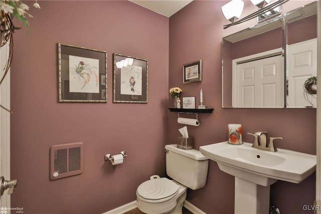 bathroom featuring heating unit, baseboards, and toilet