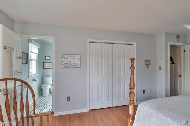 bedroom featuring baseboards, a closet, connected bathroom, and light wood-style floors