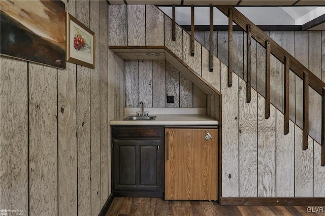 bar with dark wood-style floors, indoor wet bar, a sink, and stairway