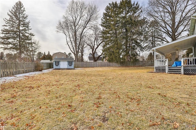 view of yard featuring a deck, a shed, an outdoor structure, and a fenced backyard