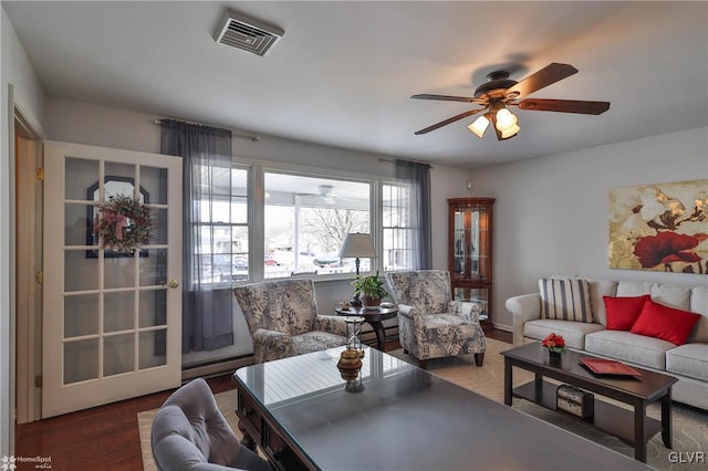 living area with a baseboard radiator, wood finished floors, visible vents, and a ceiling fan