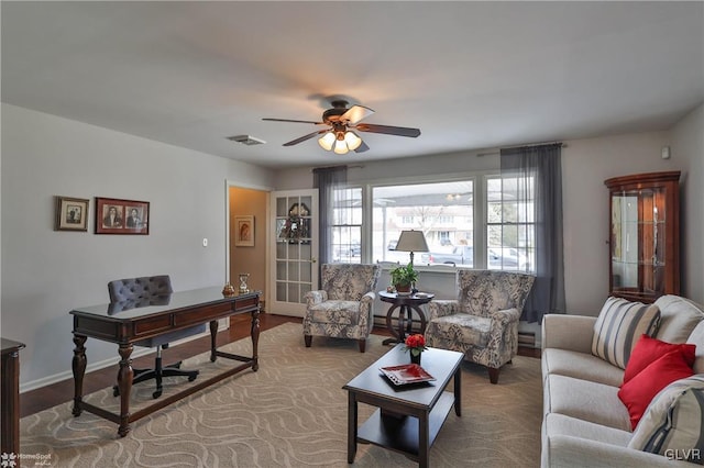 living area with a ceiling fan, visible vents, and baseboards