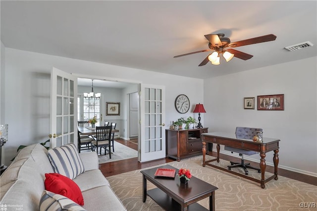 living area featuring ceiling fan with notable chandelier, french doors, visible vents, and wood finished floors