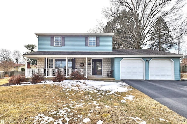 traditional-style home with aphalt driveway, covered porch, a garage, brick siding, and a lawn