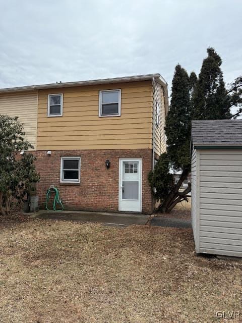 rear view of house with an outbuilding and brick siding