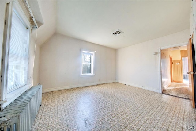 empty room with baseboards, visible vents, and vaulted ceiling