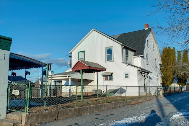 view of side of property with roof with shingles, a chimney, and fence private yard