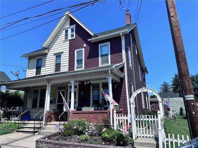 view of front of house featuring covered porch, a chimney, and fence