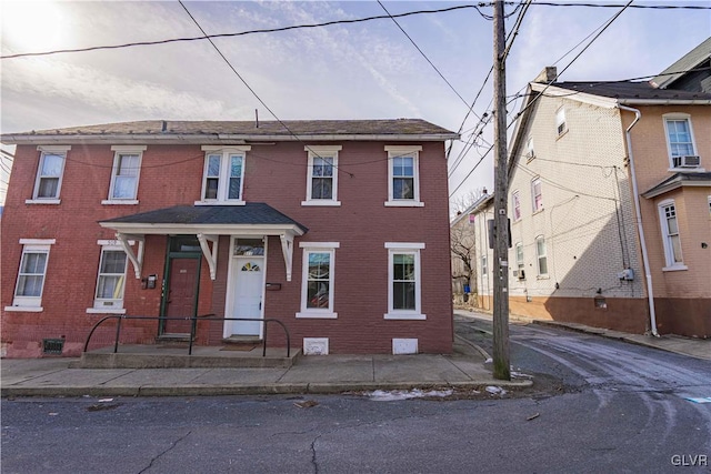 townhome / multi-family property with cooling unit and brick siding