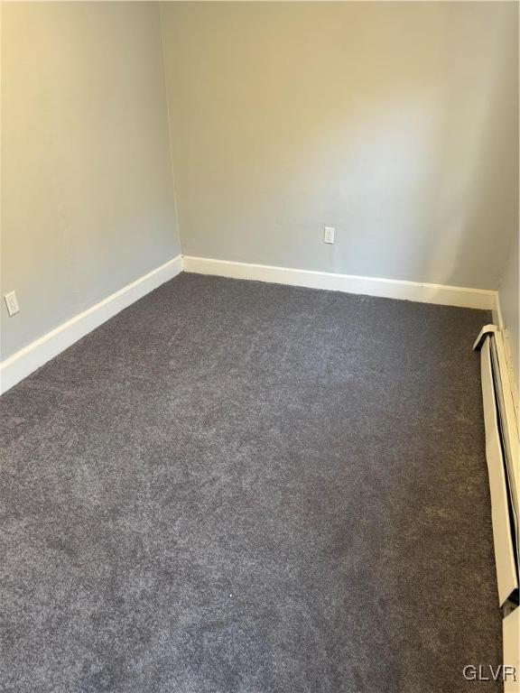 unfurnished room featuring dark carpet, a baseboard radiator, and baseboards