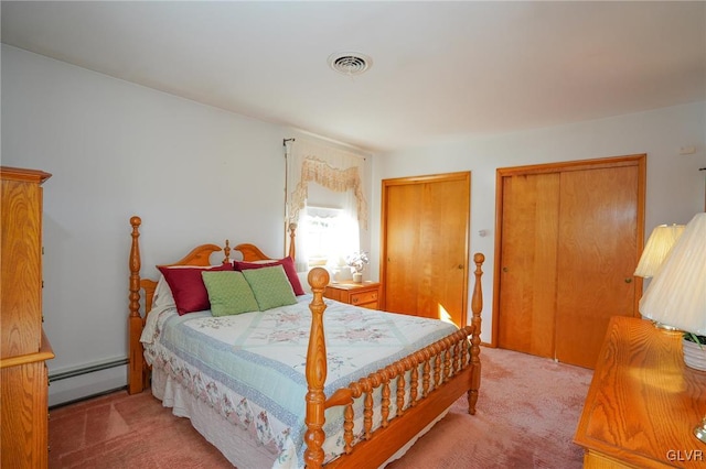 carpeted bedroom with a baseboard radiator, visible vents, and two closets