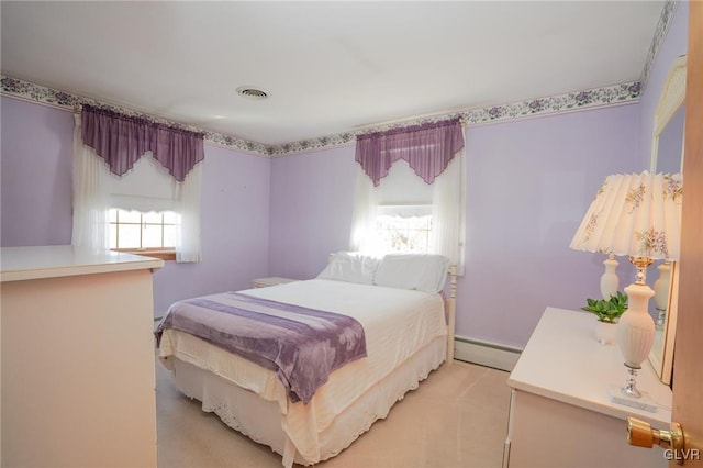 bedroom featuring visible vents, baseboard heating, and light colored carpet