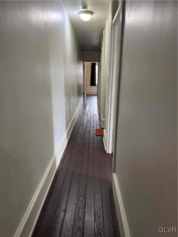 corridor with dark wood finished floors and baseboards