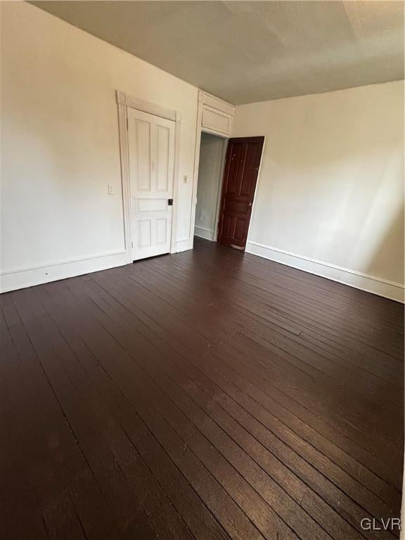 unfurnished room with dark wood-style floors and baseboards