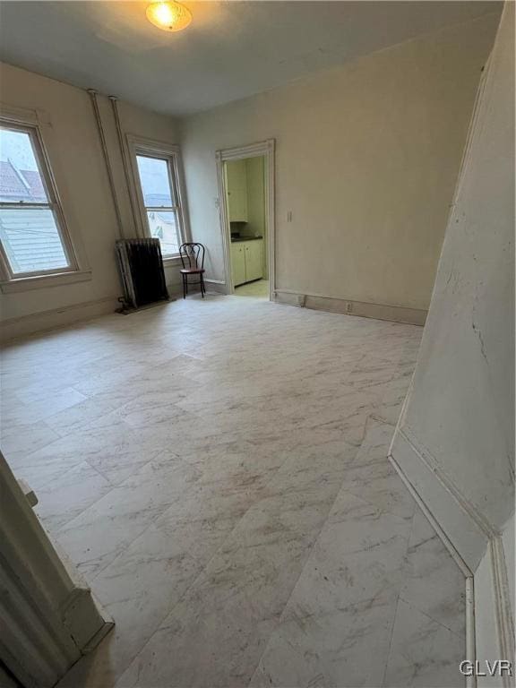 unfurnished room with marble finish floor and baseboards