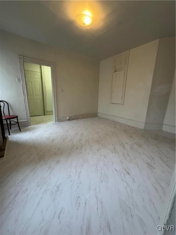 spare room with marble finish floor and baseboards