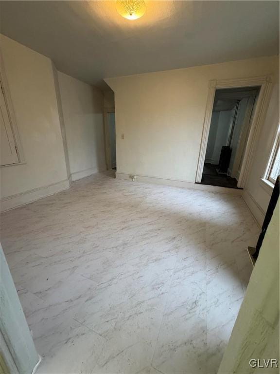 empty room featuring marble finish floor and baseboards