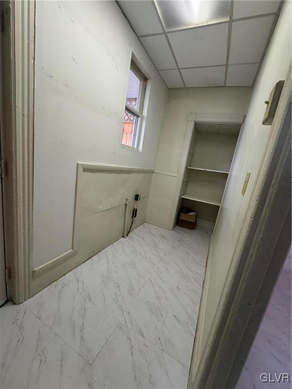 bathroom with marble finish floor and a drop ceiling