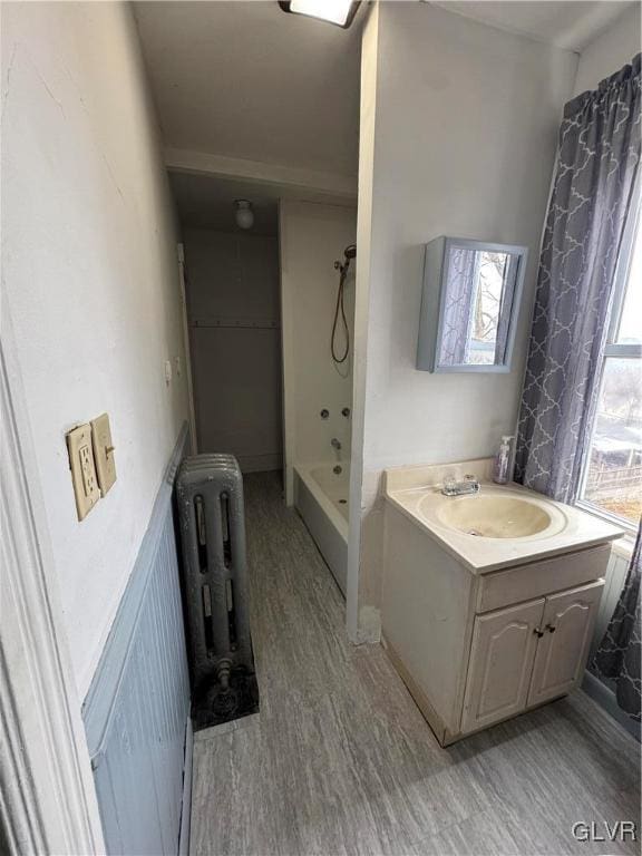 bathroom featuring a shower, vanity, radiator heating unit, and wood finished floors