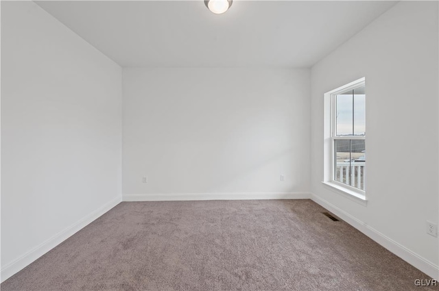 carpeted spare room featuring baseboards and visible vents